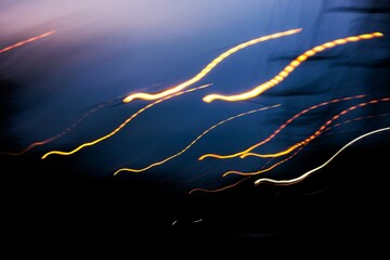 a blurry, colorful, and dynamic representation of a car's tail lights. The streaks of light create...