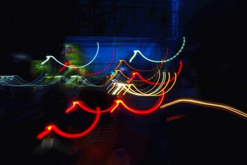 a blurry, colorful, and dynamic representation of a city street at night. The lights from cars and...