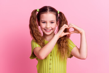 Photo portrait of pretty little girl show heart gesture wear trendy green outfit isolated on pink...