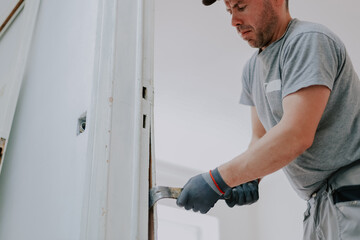 Hands of a man working with a crowbar indoors.