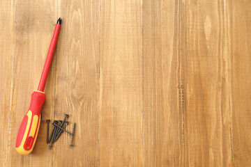 Screwdriver with red handle and screws on table, flat lay. Space for text