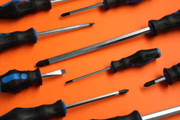 Set of screwdrivers on orange background, flat lay