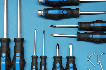 Set of screwdrivers and screws on blue background, flat lay