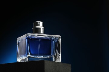 Luxury men`s perfume in bottle against dark background, low angle view. Space for text