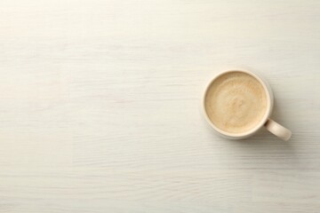 Cup of coffee on white wooden table, top view. Space for text