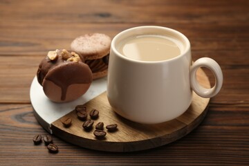 Cup of coffee and delicious macarons on wooden table