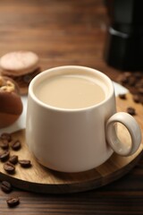 Cup of coffee and delicious macarons on wooden table, closeup