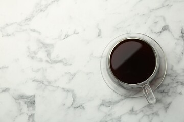 Hot coffee in cup on white marble table, top view. Space for text