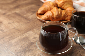 Obraz premium Hot coffee in glass cup on wooden table, closeup. Space for text