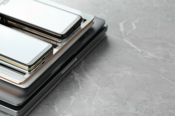 Stack of electronic devices on grey stone table, closeup. Space for text
