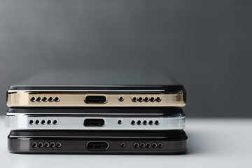 Stack of modern smartphones on white table, closeup. Space for text