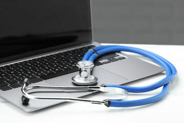 Stethoscope and modern laptop on white table