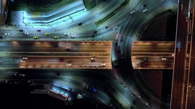 Financial technology, energy power, beautiful top view time-lapse of car traffic at roundabout lane and buildings. 4K drone aerial zoom out. Urban cityscape concept or abstract of advanced innovation.