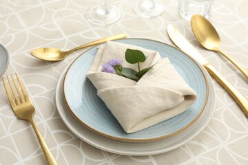 Stylish setting with cutlery, plates, napkin and floral decor on table