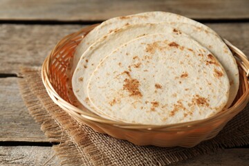 Tasty homemade tortillas in wicker basket on wooden table