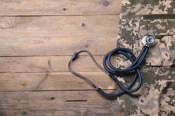 Stethoscope and military uniform on wooden background, flat lay. Space for text