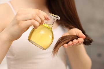 Woman applying oil hair mask indoors, closeup