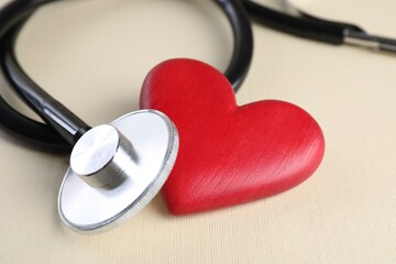 Stethoscope and red heart on beige background, closeup