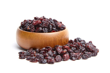 A wooden bowl filled with dried cranberries, with some cranberries spilled beside it, isolated on a white background. Dried berries with rich red color and wrinkled texture