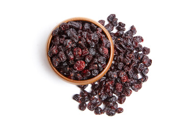 A wooden bowl filled with dried cranberries, with some cranberries spilled beside it, isolated on a white background, top view. Dried berries with rich red color and wrinkled texture