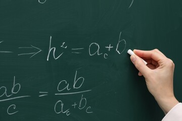 Teacher writing down math equation on green board, closeup