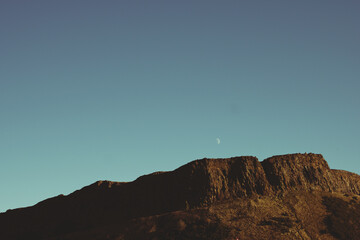 Moon rising over Salisbury Crags cliffs in Edinburgh, Scotland
