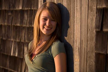 Fototapeta premium Young Woman Stands Against Old Wooden Building