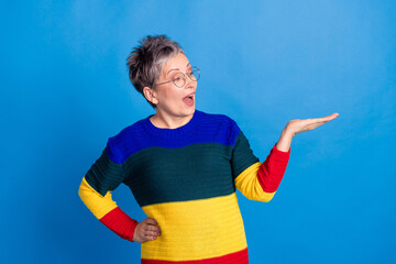 Photo of lovely adorable retired woman wear trendy clothes hold empty space offer isolated on blue...