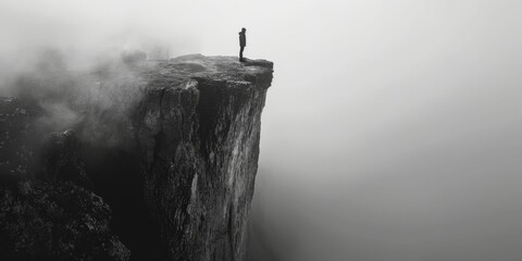 A person standing at the edge of a cliff with negative space, monochrome