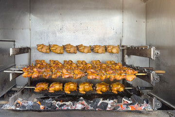 Grilled chicken, fried until golden brown. A stack of rotisserie chicken on a spit, roasted in a commercial oven. Street fast food or food.