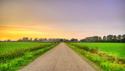 Sunset falls over an empty country road in a rural landscape in The Netherlands.