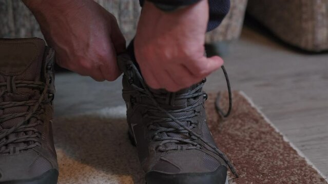 Person laces up hiking winter boots indoors. Close up of man put on trackers, and preparing himself