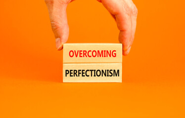 Overcoming perfectionism symbol. Concept words Overcoming perfectionism on beautiful wooden block. Beautiful orange background. Businessman hand. Business Overcoming perfectionism concept. Copy space.