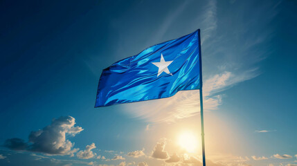 The national flag of Somalia, a blue field with a white star, waving under a bright sky.
