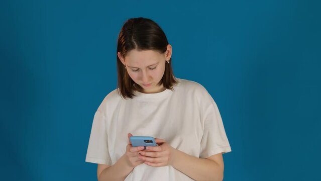 Concentrated woman with smartphone searches for available tickets. Attentive lady engages in booking process on blue background