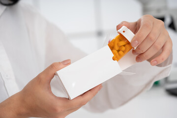 a girl medical worker takes out a medicine from a white cardboard package