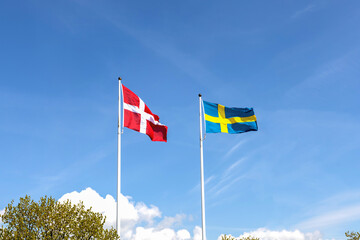 Denmark and Sweden flags against blue sky. Scandinavian national flags