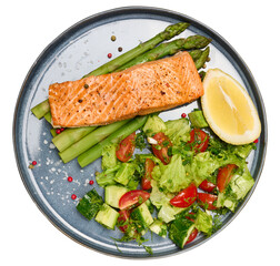 Healthy lunch with grilled salmon with asparagus and fresh tomato and cucumber salad, a row of lemon slice.