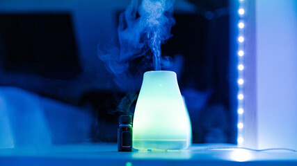 An electric air freshener and a bottle of aromatic oil are on the table.