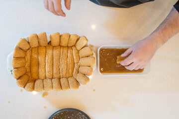 dipping a vanilla bean in coffee with milk for a tiramisu recipe, top view