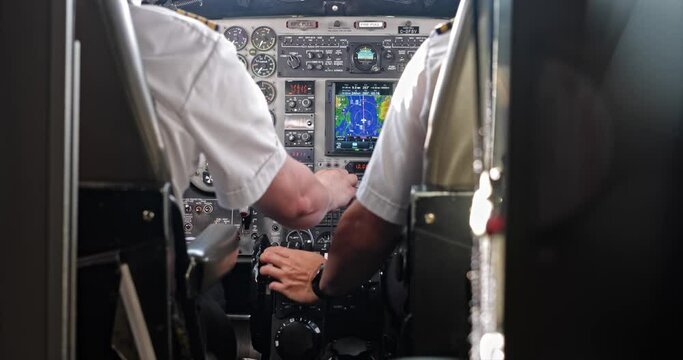 Two pilots operate small aircraft cockpit