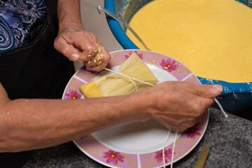 Preparing tamale with green corn cobs in the pan.