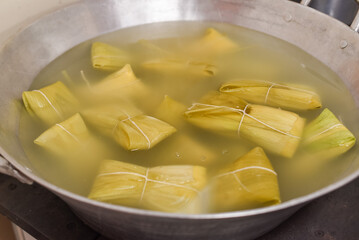 tamale with green corn cobs cooking in the pan