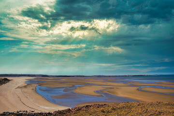Tidal flats with natural channels near Cossack, in the Pilbara region of Western Australia, under a dramatic sky.
