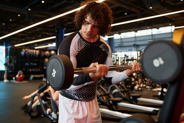 Waist up portrait of young muscular man lifting weights during strength training in gym copy space