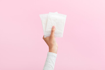 The girl is holding feminine sanitary pads in her hands. Pink background. Period. Top view. Space for text.