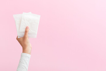 The girl is holding feminine sanitary pads in her hands. Pink background. Period. Top view. Space for text.
