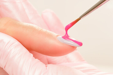 Close up process of applying pink varnish. Pink nail polish and brush, macro. Nail polish and brush, macro. Shallow depth of field