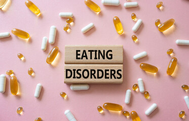 Eating Disorders symbol. Concept word. Eating Disorders on wooden blocks. Beautiful pink background...