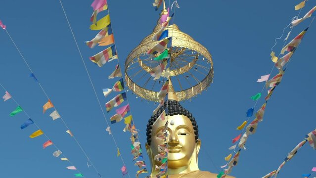 golden buddha head and flags against blue sky